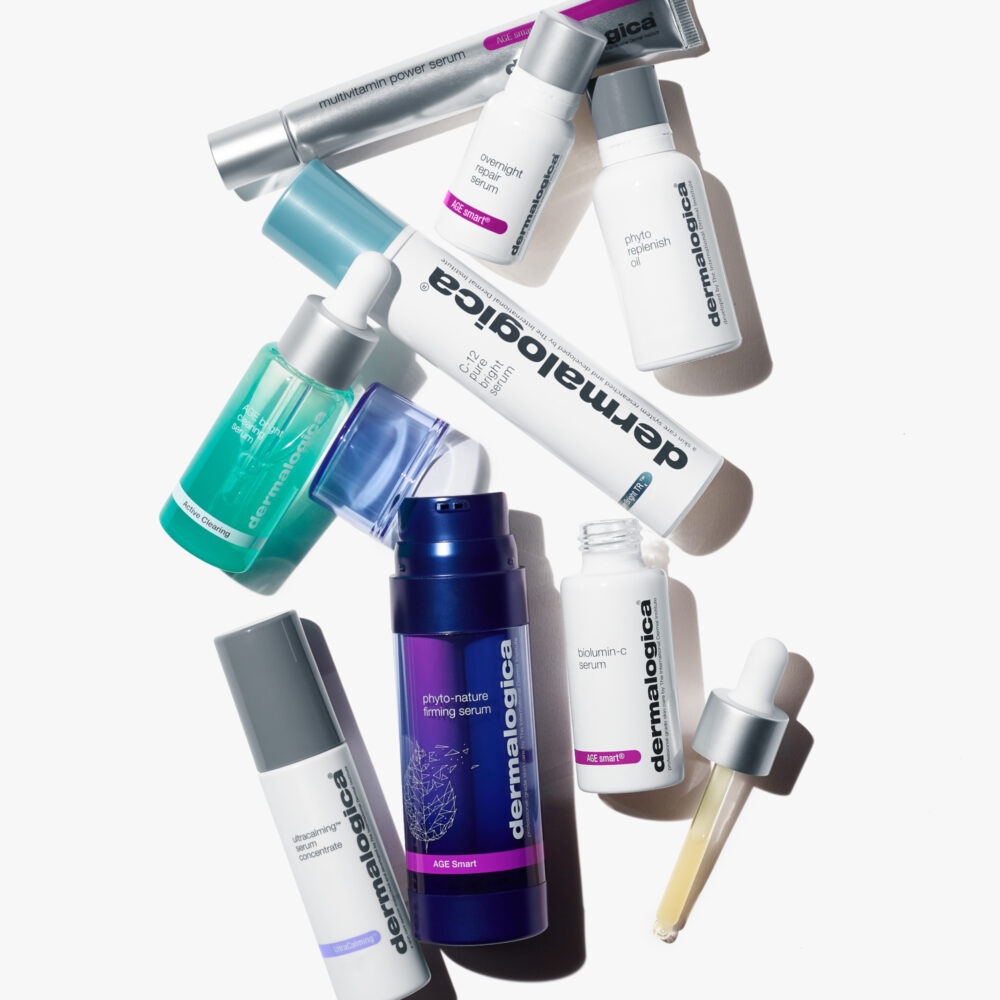 An assortment of Dermalogica products lying on a white table all jumbled together.